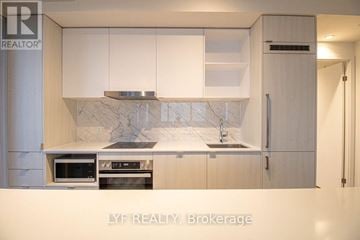 Toronto (Waterfront Communities) condo for rent - A modern kitchen with white cabinets and a marble backsplash.