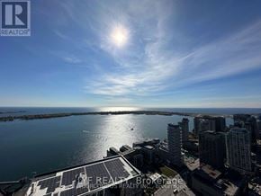 Toronto (Waterfront Communities) condo for rent - A cityscape with a bright sun in the sky.