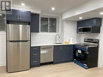 Whitby apartment for rent - A modern kitchen with a stainless steel refrigerator and black cabinets.