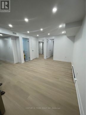 Whitby apartment for rent - A spacious room with wooden flooring and white walls, with a door on the left side.