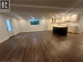 Hamilton apartment for rent - A room with wooden flooring and a kitchen area with white cabinets.