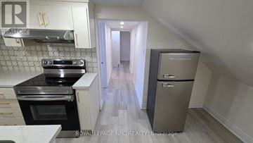 St. Catharines (E. Chester) triplex for rent - A kitchen with a stove top oven and a refrigerator.