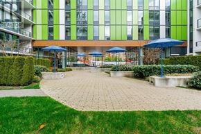 Vancouver apartment for rent - A building with a green and white facade has a patio with umbrellas.