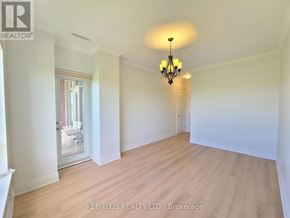Whitchurch-Stouffville (Stouffville) condo for rent - A large empty room with a chandelier and a door leading to another room.