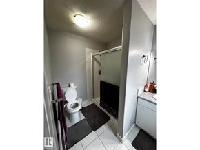 Edmonton apartment for rent - A bathroom with a toilet, sink, and mirror.