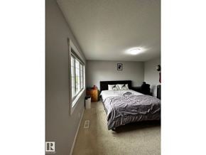 Edmonton apartment for rent - A bedroom with a bed, nightstand, and window.