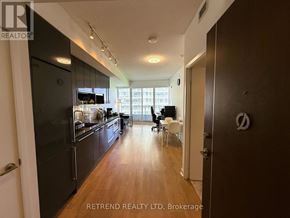 Toronto (Bayview Village) condo for rent - A modern kitchen with dark wood cabinets and a large island with a sink.