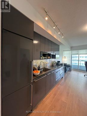 Toronto (Bayview Village) condo for rent - A kitchen with dark wood cabinets and a refrigerator with a bowl of carrots on the counter.
