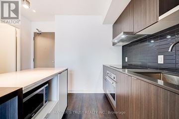 Toronto (Waterfront Communities) condo for rent - A kitchen with dark wood cabinets and stainless steel appliances.