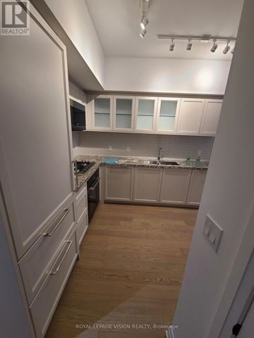 Toronto (Englemount-Lawrence) condo for rent - A kitchen with white cabinets and a wooden floor.