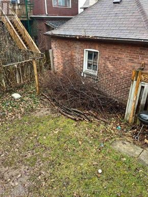 Hamilton (St. Clair) duplex for rent - A small brown brick building with a white window sits in a yard with a wooden fence and a metal grate.