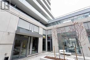 Toronto (Niagara) condo for rent - A modern building entrance with glass doors and a tree in front.