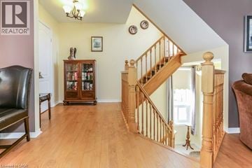Cambridge townhouse for rent - A living room with a brown leather chair and a wooden staircase.
