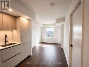Toronto (North St. James Town) condo for rent - A kitchen with wooden cabinets and a window overlooking a cityscape.
