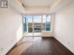 Toronto (North St. James Town) condo for rent - A large, empty room with a view of the city through the windows.