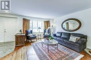 Toronto (Kingsway South) apartment for rent - A living room with a grey couch, a wooden side table, and a round mirror on the wall.