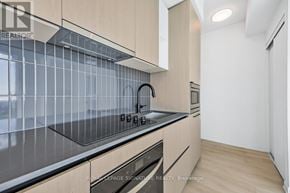 Toronto (Dovercourt-Wallace Emerson-Junction) condo for rent - A modern kitchen with wooden cabinets and a glass backsplash.