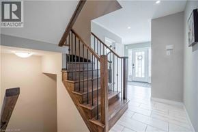 Stoney Creek townhouse for rent - A wooden staircase with a metal railing leads to a brightly lit room.