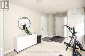 Hamilton (Ancaster) townhouse for rent - A white room with a mirror, a plant, a white dresser, a black trash can, a black exercise bike, and a black mat.