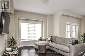 Hamilton (Ancaster) townhouse for rent - A living room with a grey couch, a black and white pillow, a black television and a black coffee table.