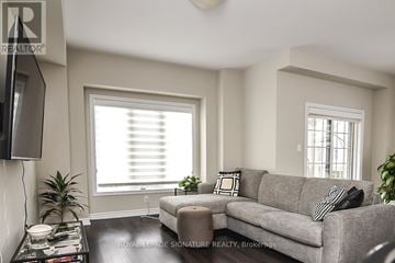 Hamilton (Ancaster) townhouse for rent - A living room with a grey couch, a black and white pillow, a black television and a black coffee table.