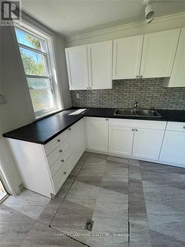 Asphodel-Norwood apartment for rent - A kitchen with white cabinets and a black countertop.