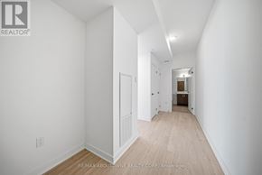Hamilton (Riverdale) condo for rent - A white hallway with wood flooring and a door on the left.