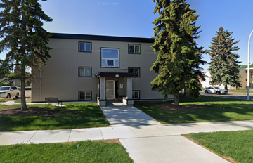 Edmonton apartment for rent - A building with a grey facade and a brown roof with a sign on it.