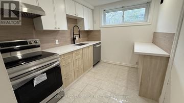 Richmond Hill (Crosby) apartment for rent - A kitchen with white cabinets and a black stove top oven.