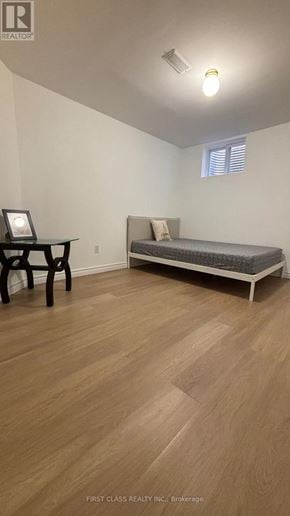Toronto (Agincourt North) apartment for rent - A bedroom with a bed, chair, and wooden flooring.