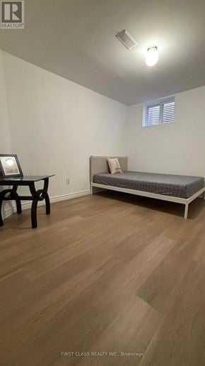 Toronto (Agincourt North) apartment for rent - A bedroom with a bed, chair, and wooden flooring.