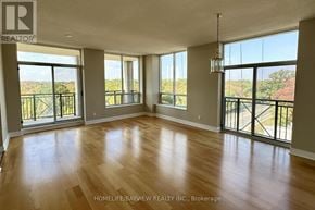 Toronto (Banbury-Don Mills) condo for rent - A spacious room with wooden floors and large windows overlooking a balcony.