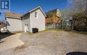 Barrie (Codrington) duplex for rent - A house with a grey siding and a brown roof is surrounded by a gravel driveway and a fence.