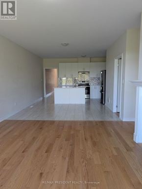 Grey Highlands townhouse for rent - A large, empty room with wooden flooring and a kitchen area in the background.