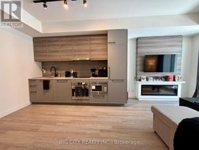 Toronto (The Beaches) condo for rent - A modern kitchen with a large island and a TV mounted on the wall.