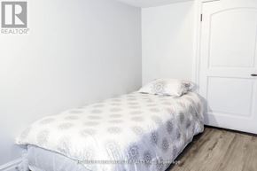 Toronto (Trinity-Bellwoods) apartment for rent - A white bed with a white patterned duvet cover sits in a room with a white door.