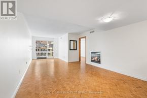 Toronto (Bay Street Corridor) condo for rent - A spacious room with a fireplace and a view of a cityscape through the window.