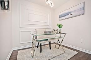Pickering (Duffin Heights) townhouse for rent - A glass dining table with a metal base and a glass top is placed in a room with white walls and a white framed picture hanging on the wall above it.