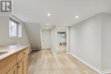 Toronto (Lawrence Park North) apartment for rent - A spacious room with wooden flooring and white walls, furnished with a kitchen area.