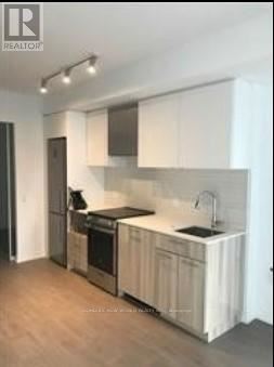 Toronto (Church-Yonge Corridor) condo for rent - A kitchen with white cabinets and a wooden floor.