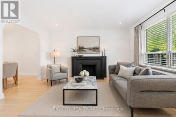 Toronto (Leaside) apartment for rent - A living room with a grey couch, a fireplace, and a painting on the wall.