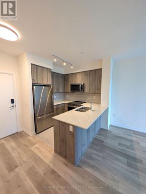 Mississauga (Hurontario) condo for rent - A modern kitchen with wooden cabinets and a white countertop.