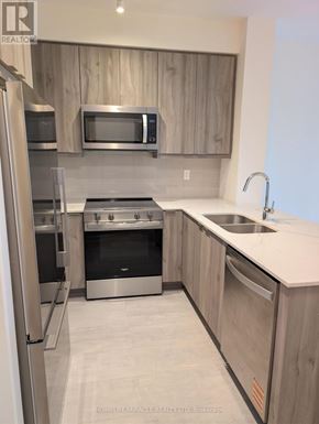Mississauga (Hurontario) condo for rent - A modern kitchen with stainless steel appliances and wooden cabinets.