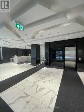 Toronto (Mount Pleasant East) condo for rent - A hallway with a marble floor and a green exit sign.