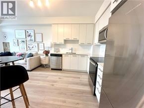 Grimsby condo for rent - A modern kitchen with white cabinets and a stainless steel refrigerator.