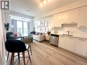 Grimsby condo for rent - A well-lit kitchen with white cabinets and a dining table with chairs.