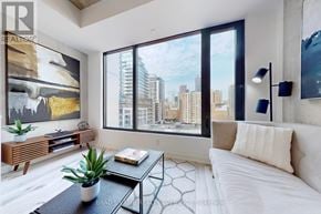 Toronto (Moss Park) condo for rent - A modern living room with a large window overlooking the city.