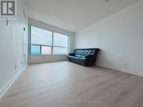 Toronto (Woburn) condo for rent - A black couch sits in a spacious room with a large window.