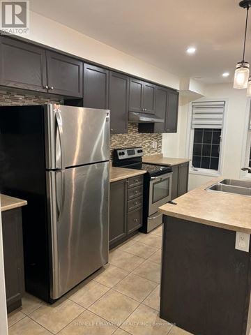 Markham (Berczy) townhouse for rent - A modern kitchen with a stainless steel refrigerator and dark brown cabinets.