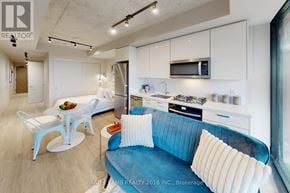 Toronto (Kensington-Chinatown) condo for rent - A modern kitchen with white cabinets and a blue couch.